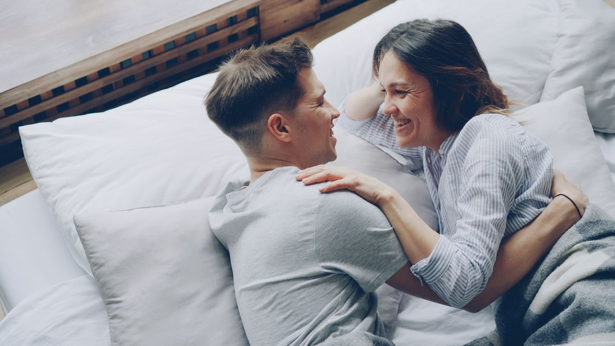 Relaxed, happy couple laughing together in bed