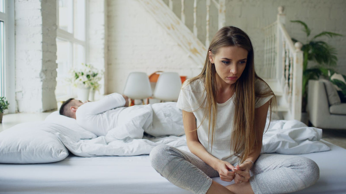 A thoughtful person sitting on a bed