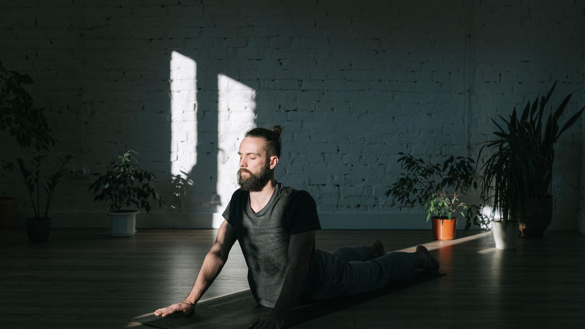Calm man meditating in sunlight at home