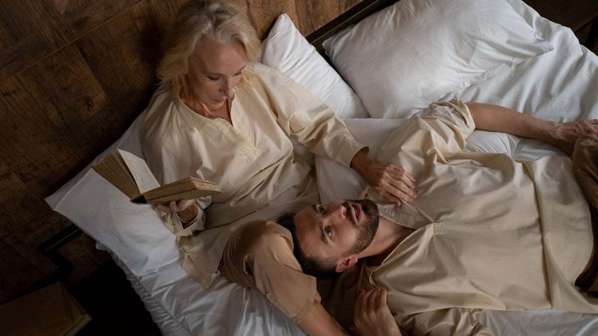A couple lying in bed a little distant